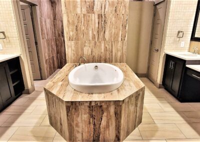 Large master bathroom with his and her vanities separated by garden tub on tiled platform.